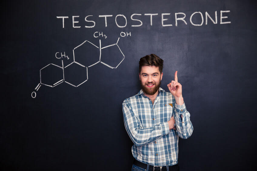 黒板の背景に描かれたテストステロン分子の化学構造に上向き自信の笑みを浮かべて若い男
